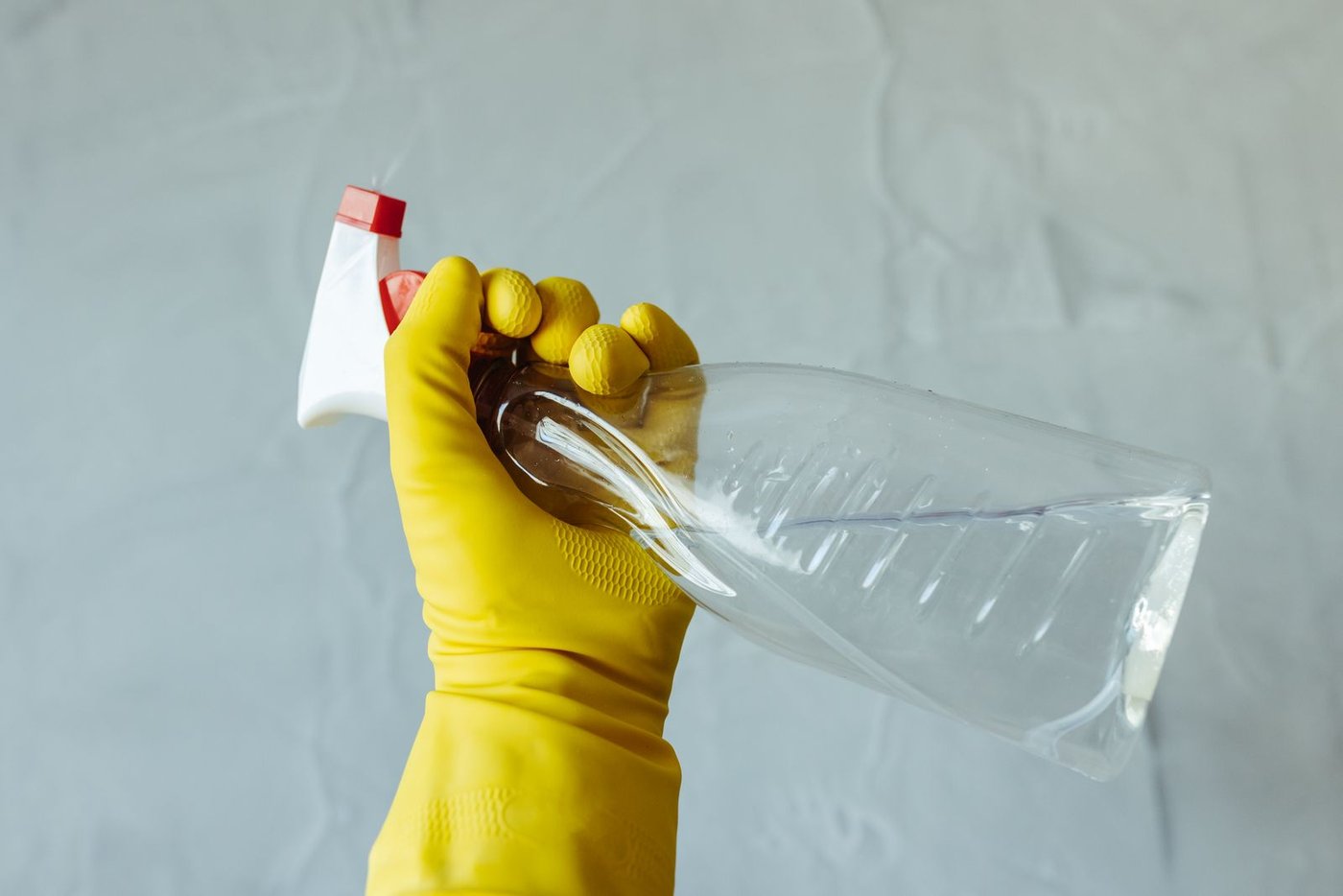 A gloved hand with a cleaning spray bottle, part of a fall deep cleaning product roundup.