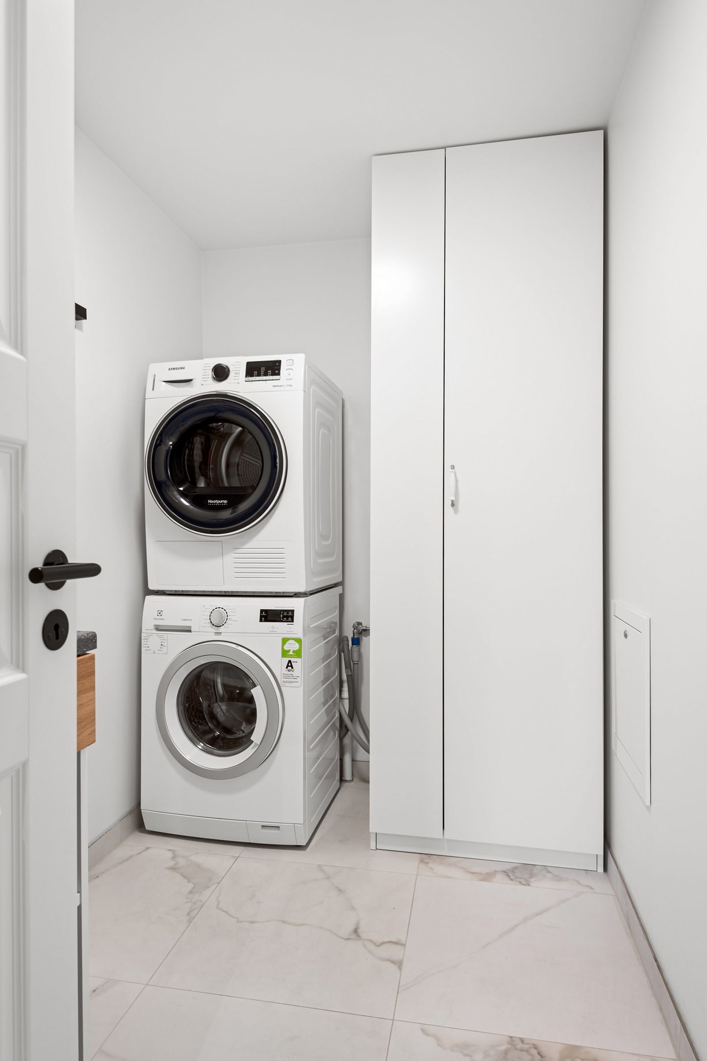 A bright, tidy laundry room with a stacked washer and dryer, set up for a smoother routine.
