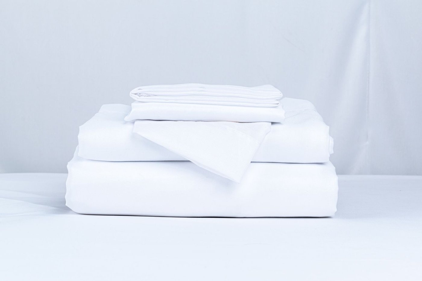 A neat stack of clean white folded bedding linens, ready to be sorted for the season.