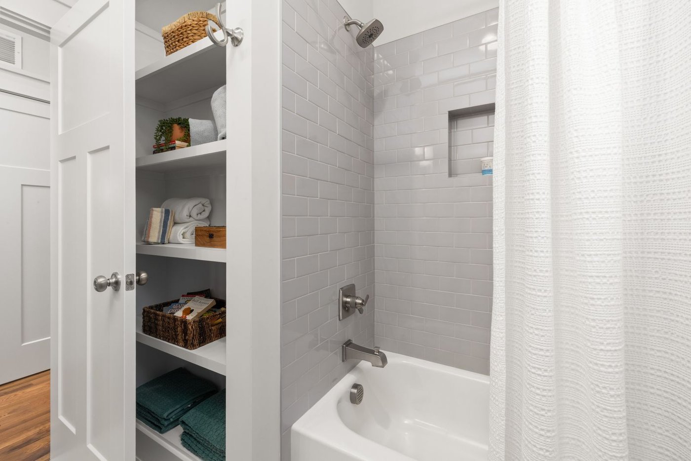 A small bathroom with a built-in shelving unit maximizing storage next to the shower.