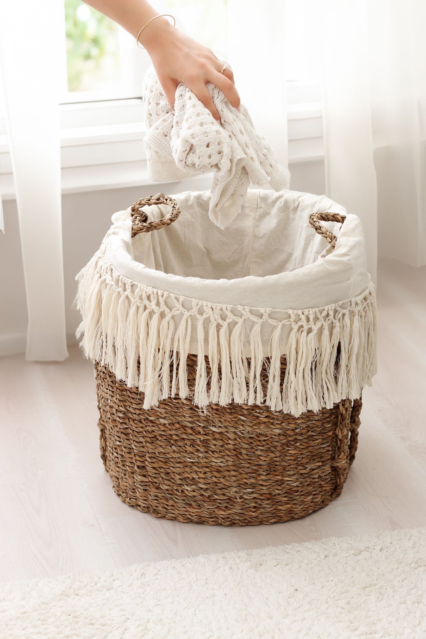 A hand placing folded laundry into a woven basket, part of a smoother laundry routine.